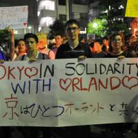 People at a candlelight vigil Tuesday evening in Tokyo\'s Shinjuku Ni-chome district show their solidarity with people in Orlando, Florida, where a gunman killed scores at a gay nightclub Sunday. | YOSHIAKI MIURA