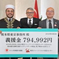 Imam and Director of the Tokyo Camii and Turkish Culture Center Muhammed Rasit Alas (left) and Junichi Watanabe (right), director general of the Tokyo office of the Kumamoto Prefectural Government, are joined by Turkish Ambassador Ahmet Bulent Meric as the center presents the prefecture with a &#165;794,992 donation, raised from the proceeds of a Kumamoto earthquake reconstruction charity bazaar, at the Turkish Embassy in Tokyo on June 2. | YOSHIAKI MIURA