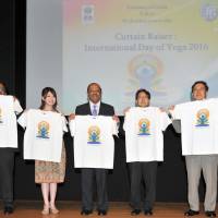 From left: Tech Mahindra Vice President and Head of North Asia Amitava Ghosh; Jury\'s Special Award winner and Miss World Japan 2015 Akiko Kato; Ambassador of India Sujan R. Chinoy; Japan Sports Authority Director General Tetsuya Kimura; and Maharishi Institute of Total Education Representative Director Shizuo Suzuki hold T-shirts bearing the logo for the second International Day of Yoga opening event at the Vivekananda Cultural Centre of the Indian Embassy in Tokyo on June 9. | YOSHIAKI MIURA