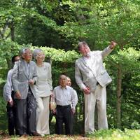 Emperor Akihito and Empress Michiko listen to Japan Times columnist C.W. Nicol during a stroll through the Afan Woodland in the town of Shinano, Nagano Prefecture, on Monday. The noted environmentalist has long been involved in efforts to restore the woodland\'s original ecosystem. | POOL / KYODO