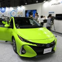 A plug-in version of Toyota Motor Corp.\'s Prius model is unveiled during Smart Community Japan, a renewable energy trade show that kicked off Wednesday at Tokyo Big Sight in Koto Ward. The Prius PHV has solar panels on its roof that recharge its batteries while driving and at rest. | KAZUAKI NAGATA