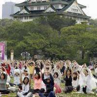 Around 700 yoga enthusiasts celebrate International Yoga Day two days early in a park adjacent to Osaka Castle in Chuo Ward, Osaka, on Sunday. | KYODO