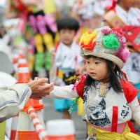 A girl touches the hand of an onlooker Sunday as she marches in a parade through the city of Aomori during the Tohoku Rokkon Festival (Tohoku Big 6 Festival). The festival was first held in Sendai in July 2011, four months after the March 2011 earthquake and tsunami, to pray for reconstruction of the Tohoku region. | KYODO