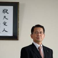 Tomoaki Horiguchi, president and CEO of Sun Frontier Fudousan Co., is seen in his Tokyo office. The phrase on the wall is “Keiten aijin,” or “Live in awe of God and love people.” It is attributed to Buddhist monk and Kyocera Corp. Kazuo Inamori. Hotel tycoon Horiguchi finds making people happy brings reward