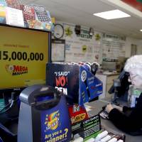 A customer waits for her Mega Millions lottery ticket at a convenience store in Chicago Friday. | AP