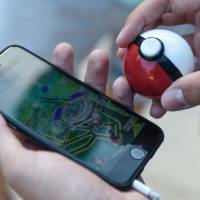 A gamer plays \"Pokemon Go\" in Barcelona on July 14. The popular game has increased the share prices of Tomy Co., Bank of Kyoto Ltd. and more. | AFP-JIJI