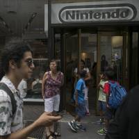 Gamers play \"Pokemon Go\" outside a Nintendo Co. store at New York\'s Rockefeller Center on July 13. | BLOOMBERG