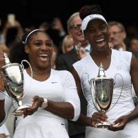Serena Williams (left) and Venus Williams celebrate winning their women\'s doubles final on Thursday in the London suburb of Wimbledon. | REUTERS