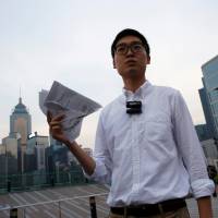 Pro-independence Hong Kong National Party convenor Chan Ho-tin holds a form saying the city is an \"inalienable\" part of China, which he has torn into pieces, after being disqualified from running in Legislative Council elections on Saturday. | REUTERS