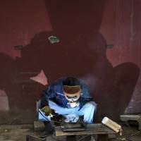 A welder works at a construction site in Beijing on Sunday. | AP