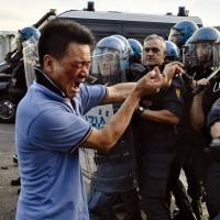 Italian police officers in riot gear push back a protester during clashes with members of the local Chinese community in Sesto Fiorentino, a suburb on the outskirts of Florence, Italy, on Thursday. | AP