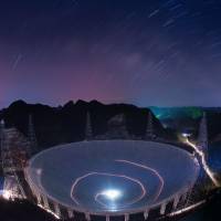 A vehicle leaves light trails in a long-exposure photo of the Five-hundred-meter Aperture Spherical Telescope in Pingtang County in southwestern China\'s Guizhou Province on Monday. | AP
