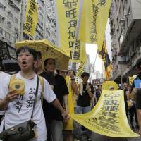 Protesters carry a banner reading \"I want genuine universal suffrage\" in Chinese during an annual pro-democracy protest in Hong Kong on Friday. A Hong Kong bookseller who was to lead the march dropped out at the last minute, saying he felt \"gravely threatened.\" | AP