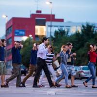 People walk with their hands up as they are evacuated from the Olympia shopping mall in Munich on Friday following a shooting that left at least 10 dead, including the gunman. | AFP-JIJI