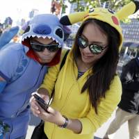 A woman dressed as the Pokemon character Pikachu (right) participates in a \"Pokemon Go\" search with a man dressed as the Disney character Stitch on Wednesday in San Francisco. | AP