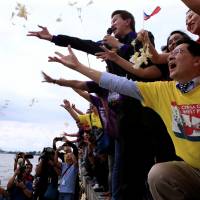Protesters throw flowers while chanting anti-Chinese slogans during a rally by different activist groups over the South China Sea dispute, along a bay in Manila on Tuesday. | REUTERS