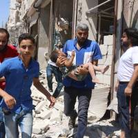 A Syrian carries a boy wounded in an airstrike on the rebel-held Aleppo neighborhood of Qatirji on Saturday. | AFP-JIJI