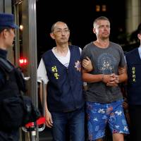 Andrejs Peregudovs from Latvia, who is suspected of stealing from an automated teller machine, is escorted at the police station in Taipei Sunday. | REUTERS