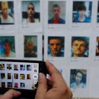 A journalist takes a photo of suspects police said are involved in stealing from automated teller machines (ATM), during a news conference in Taipei Sunday. | REUTERS