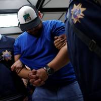 A suspect from Romania, involved in thefts from automated teller machines (ATM), is escorted at the police station in Taipei Sunday. | REUTERS