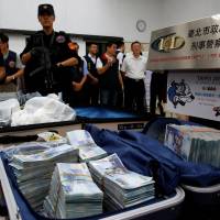 Taiwanese banknotes are displayed after they were found in a hotel room rented by one of the suspects involved in stealing from automated teller machines (ATM) in Taipei Sunday. | REUTERS