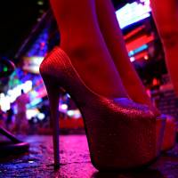 Women stand outside a bar in a red light district in Bangkok on July 12. | REUTERS