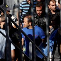 One of the eight Turkish soldiers (center) who fled to Greece in a helicopter and requested political asylum after a failed military coup against the government is escorted by special police forces after the postponement of their interviews for asylum request at the Asylum Service in Athens Wednesday. | REUTERS