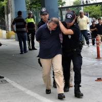 Police officers escort Adm. Atilla Demirhan and a group of millitary personal detained in Mersin, Turkey, Tuesday. | DEPO PHOTOS VIA AP