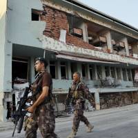 Turkish special forces policemen walk in front of their damaged base, which was attacked by the Turkish warplanes during the failed military coup last Friday, in Ankara Tuesday. The violence surrounding the Friday night coup attempt claimed the lives of 208 government supporters and 24 coup plotters, according to the government. | AP