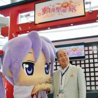 Kadokawa Corp. Chairman Tsuguhiko Kadokawa shakes hands with an animation character in Hong Kong on Wednesday to promote the Anime Tourism 88-Stop Pilgrimage project. | KYODO