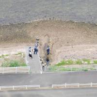 Police investigate the spot where a dismembered human body part was found Friday on the shore of Lake Hamana in Shizuoka Prefecture. | KYODO