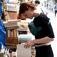 A shopper browses art books at a store selling used volumes in Tokyo’s Jinbocho neighborhood. | SATOKO KAWASAKI