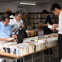 People browse used volumes at one of some 160 bookstores in Jinbocho in Tokyo’s Chiyoda Ward. | SATOKO KAWASAKI