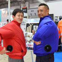Sun-S Co. employees demonstrate jackets with battery-powered cooling fans on Wednesday at Heat Solution Tokyo 2016, an expo at Tokyo Big Sight. | SATOKO KAWASAKI