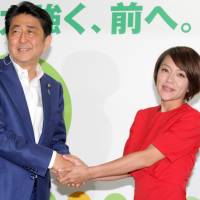 Prime Minister Shinzo Abe and singer Eriko Imai shake hands at party headquarters following the Upper House election on Sunday.  | YOSHIAKI MIURA