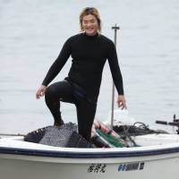 Free diver Yushi Ikeda returns from fishing with his female colleagues in Shima, Mie Prefecture, on June 19. | KYODO