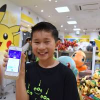 A boy shows off a smartphone displaying the action from a \"Pokemon Go\" game at a Pokemon goods shop in Tokyo on Friday. | SATOKO KAWASAKI