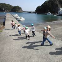 Children walk along a pier in the town of Minami-Izu, Shizuoka Prefecture. A government survey showed Wednesday that Japan\'s population as of Jan. 1 dropped at the fastest pace ever on an annual basis. | BLOOMBERG