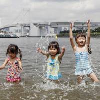 Children play in the water at a beach in Tokyo’s Odaiba area on Thursday when the weather agency announced the rainy season in the Kanto region is believed to have ended. | KYODO