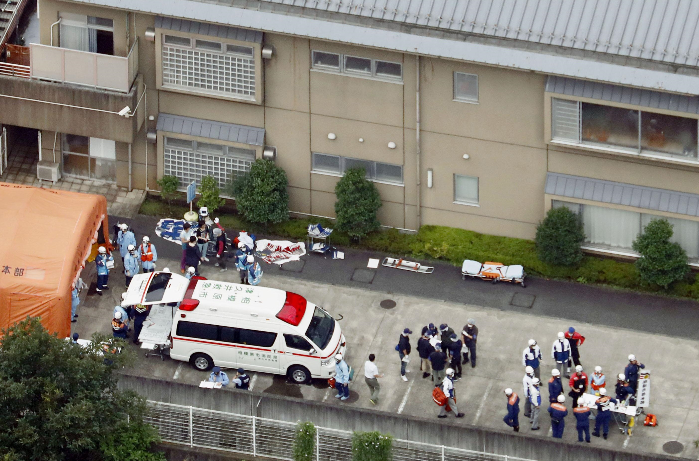 Ambulance personnel and staff at Tsukui Yamayuri En wait outside the care facility in Sagamihara, Kanagawa Prefecture, on Tuesday after a knife-wielding man broke in and killed at least 19 residents. | KYODO