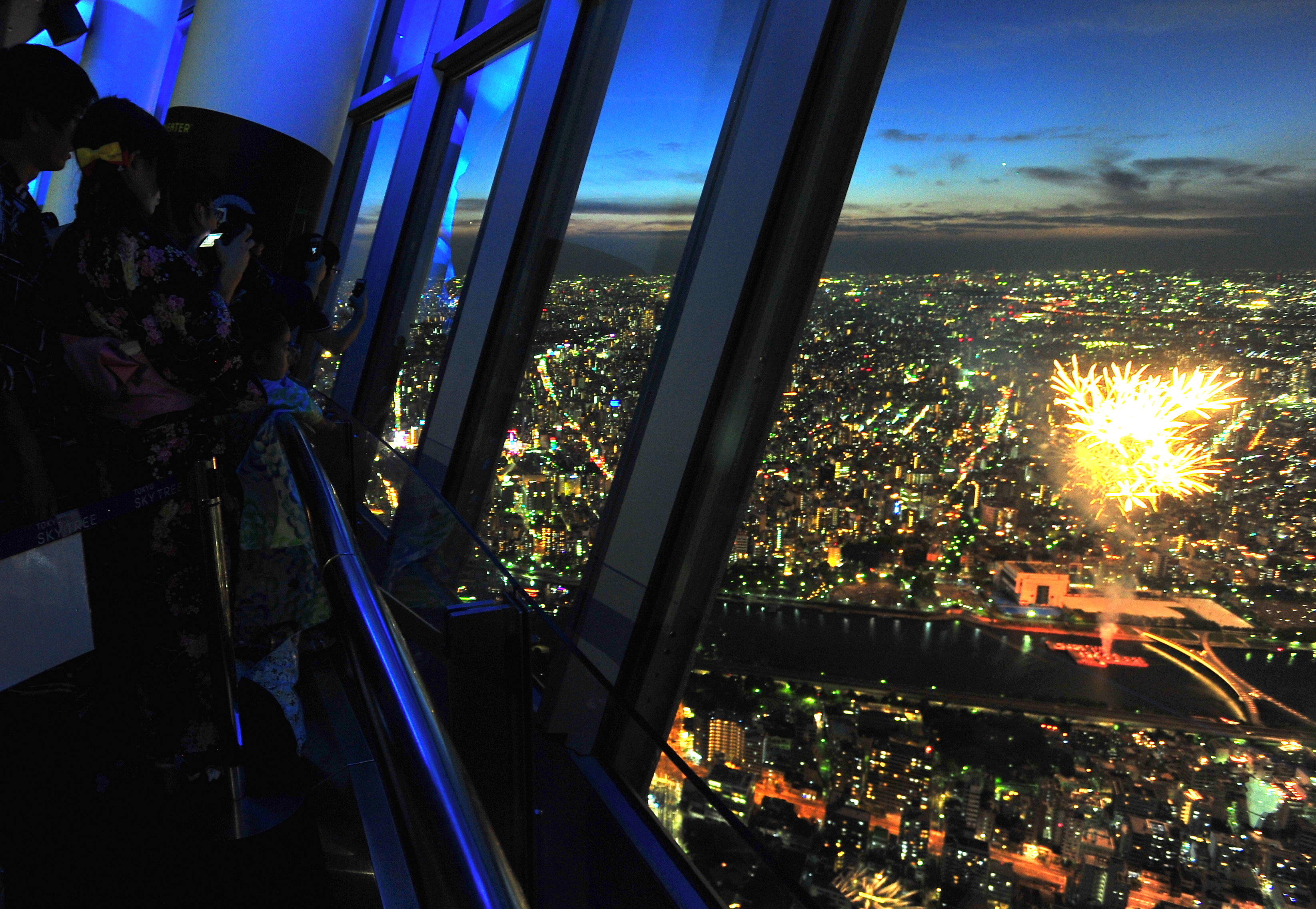 Visitors watch fireworks from Tokyo Skytree's observation deck on Saturday in Tokyo's Sumida Ward. | YOSHIAKI MIURA