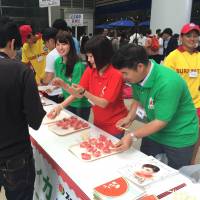 Suika Club members hand out chunks of watermelon Wednesday at Tokyo Midtown in the Roppongi district to help people stay cool. | DAISUKE KIKUCHI