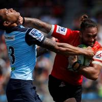 Sunwolves\' Derek Carpenter (right) tries to fend off a tackle by Waratahs\' Israel Folau in Tokyo on Saturday. | REUTERS