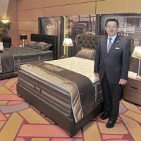 Simmons Co. President Masafumi Ito poses next to Simmons\' new \"Gran Pillow Top\" from the \"Beautyrest Luxe\" series an event introducing Simmons\' 2016-17 lineup at the Tokyo American Club on July 20. | YOSHIAKI MIURA