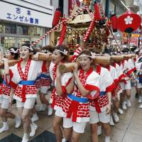 Women carry a gyaru mikoshi (girls\' portable shrine) through a shopping arcade in Osaka\'s Kita Ward on Saturday in the lead-up to the annual Tenjin Matsuri, one of the three largest summer festivals in Japan, which will be held on Sunday and Monday. | KYODO