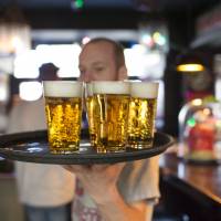 A barman carries a tray of Grolsch drafts, produced by SABMiller Plc, in a bar in Utrecht, Netherlands. Anheuser-Busch InBev NV has accepted Asahi Group Holdings Ltd.\'s offer to buy the Peroni, Grolsch and Meantime beer brands. | BLOOMBERG
