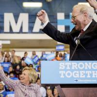 Berkshire Hathaway Chairman and CEO Warren Buffett cheers as he and Democratic presidential candidate Hillary Clinton arrive at a rally at Omaha North High Magnet School in Omaha, Nebraska, Monday. | AP