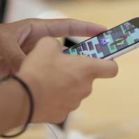 A customer tries out an Apple iPhone 6s Plus smartphone at a SoftBank store in Tokyo on July 26. | BLOOMBERG