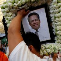 A man holds portrait of murdered Cambodian anti-government figure Kem Ley, who shot dead on July 10, during a funeral procession in Phnom Penh on July 24. | REUTERS