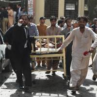 Lawyers and local media personnel carry a bed before moving the body of a news cameraman after an explosion at a government hospital in Quetta, Pakistan, on Monday. Bombing at hospital in Pakistani city of Quetta kills 53, leaves dozens wounded